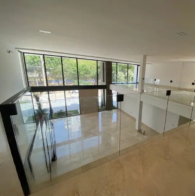 Interior espacioso y moderno con barandillas de cristal, grandes ventanas y suelos de mármol, que permiten disfrutar de la luz natural y las vistas al exterior.